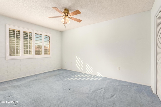 empty room with ceiling fan, carpet floors, and a textured ceiling