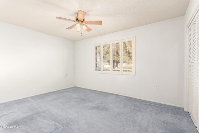 carpeted spare room with a textured ceiling and ceiling fan