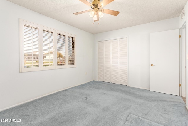 unfurnished bedroom featuring ceiling fan, a closet, carpet, and a textured ceiling