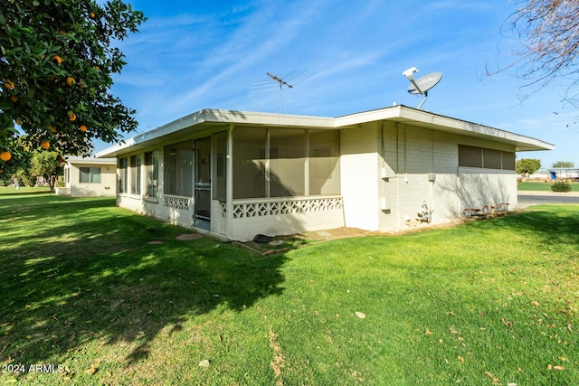 view of side of home featuring a sunroom and a yard