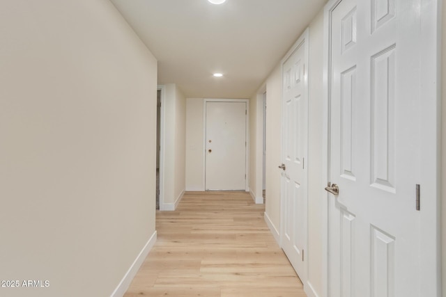 hall featuring light wood-style flooring and baseboards