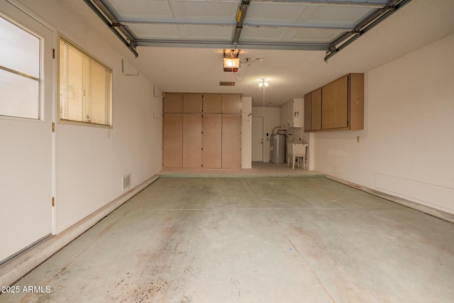 garage featuring visible vents, a garage door opener, and electric water heater