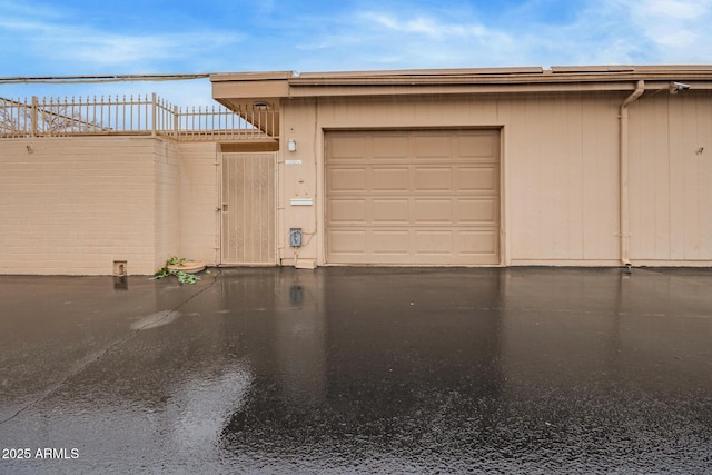 garage featuring aphalt driveway and fence