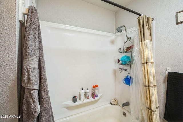 bathroom with shower / bathtub combination with curtain and a textured wall