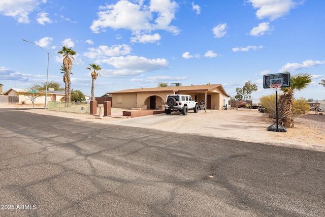 ranch-style home featuring driveway and fence