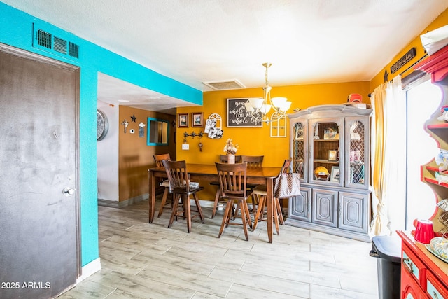 dining space with a chandelier, wood tiled floor, visible vents, and baseboards