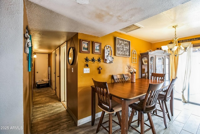 dining area featuring visible vents, a textured wall, a textured ceiling, and baseboards