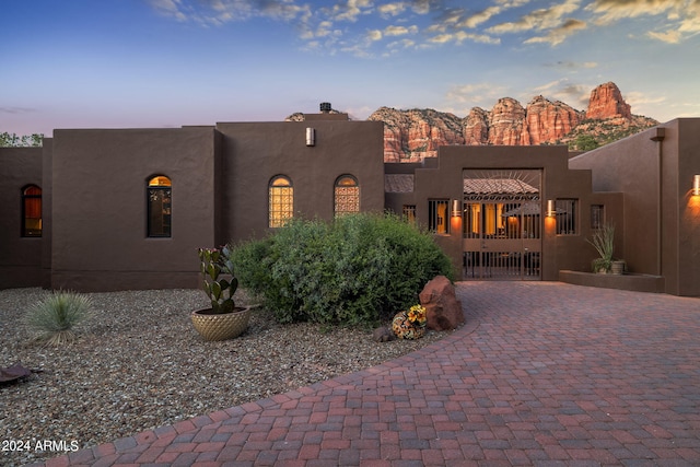 pueblo-style house featuring decorative driveway, a gate, and stucco siding