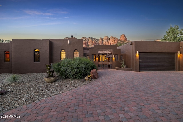 adobe home with an attached garage, decorative driveway, and stucco siding