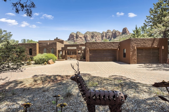 southwest-style home featuring a garage, decorative driveway, and stucco siding