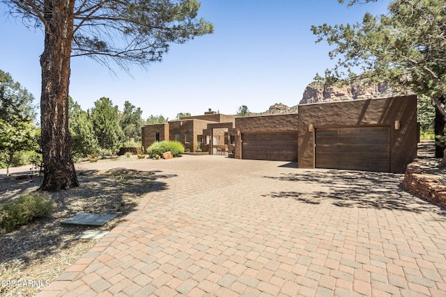 southwest-style home featuring decorative driveway, an attached garage, and stucco siding