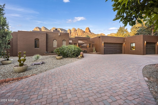 adobe home with an attached garage, decorative driveway, and stucco siding