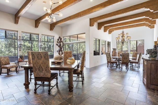 dining area featuring stone tile flooring, a notable chandelier, and beamed ceiling