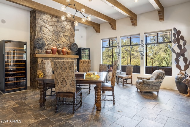 dining room featuring beam ceiling, beverage cooler, and stone tile floors