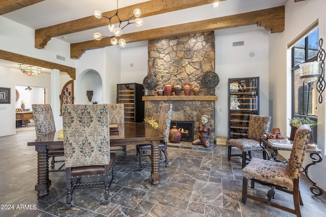 dining space with stone tile flooring, visible vents, beamed ceiling, and a stone fireplace