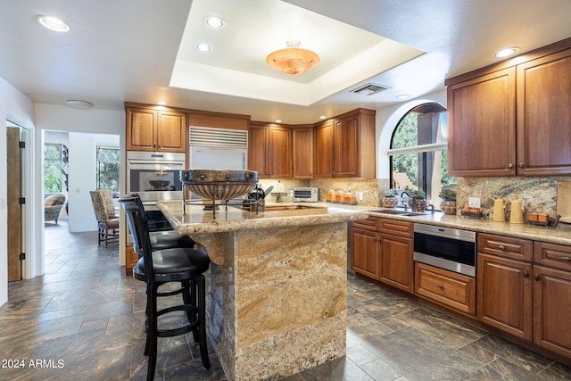 kitchen featuring visible vents, stone tile flooring, a raised ceiling, and backsplash