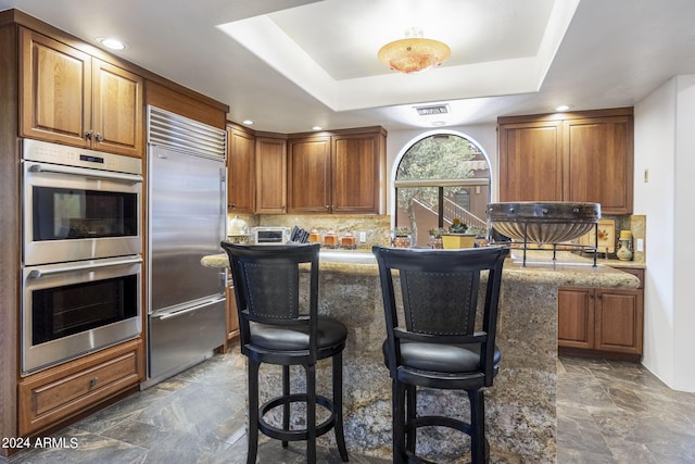 kitchen featuring tasteful backsplash, a kitchen island, appliances with stainless steel finishes, and a raised ceiling