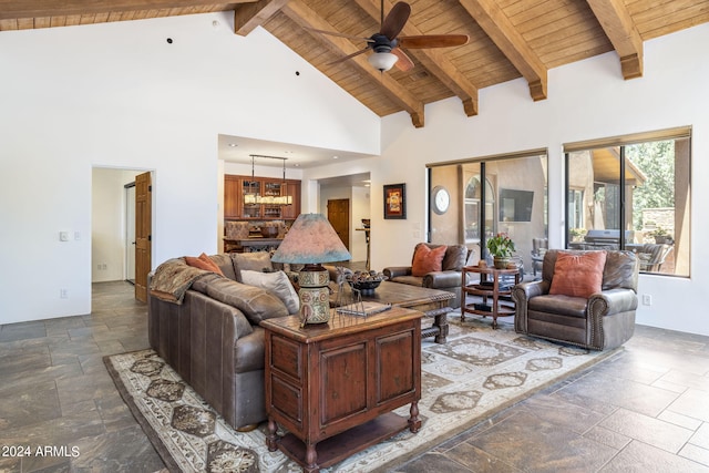 living room with wooden ceiling, beamed ceiling, stone tile flooring, high vaulted ceiling, and ceiling fan with notable chandelier