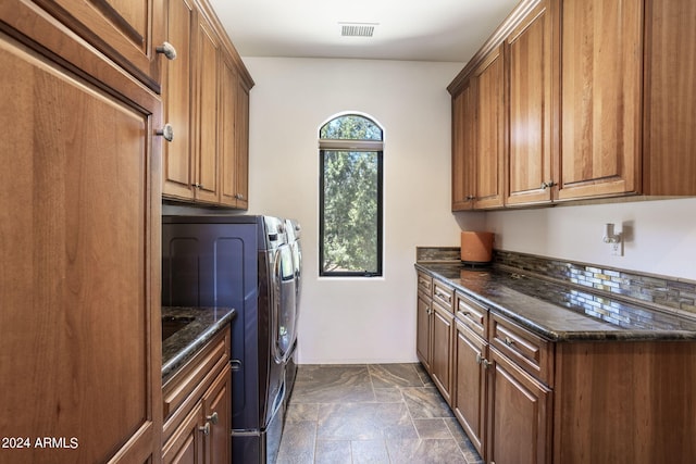 clothes washing area featuring cabinet space, washing machine and dryer, visible vents, and stone finish flooring