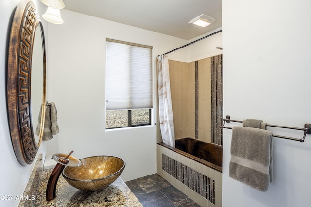 full bath featuring stone tile flooring and a tile shower