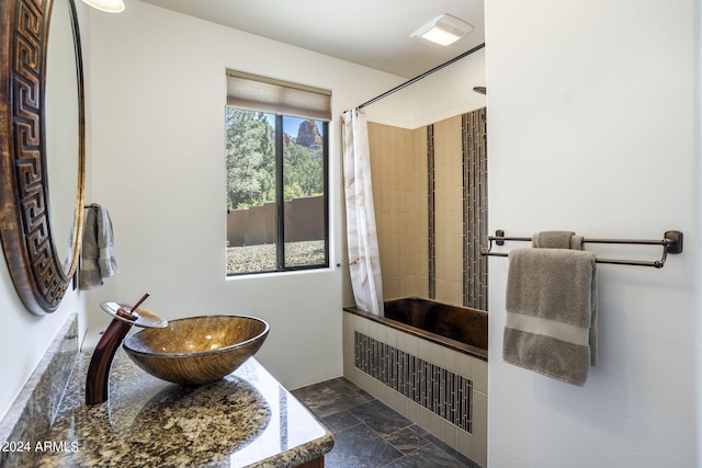 full bath featuring tiled shower, vanity, and stone tile flooring