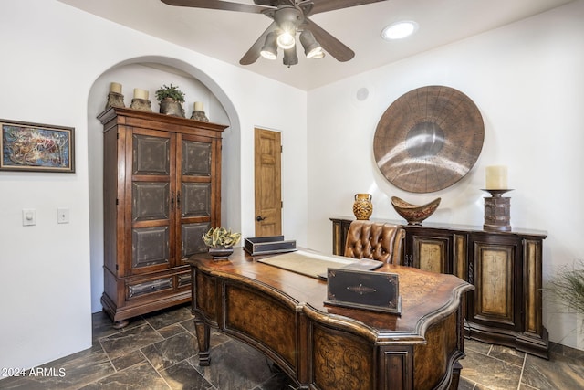 office area with arched walkways, stone finish floor, a ceiling fan, and recessed lighting