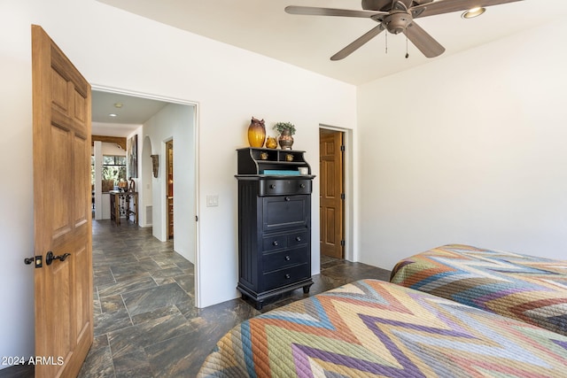 bedroom with ceiling fan and stone finish floor