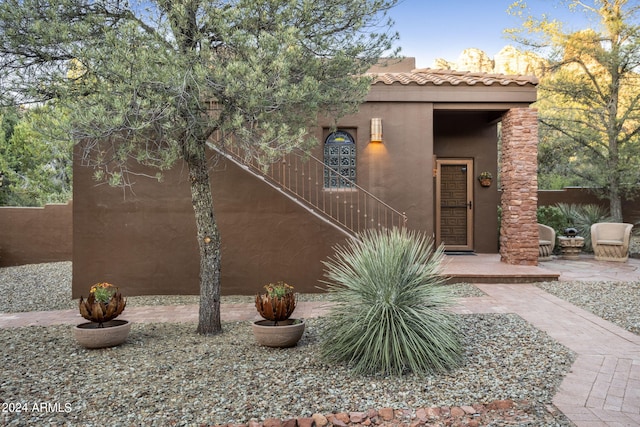 exterior space featuring a tile roof, fence, and stucco siding