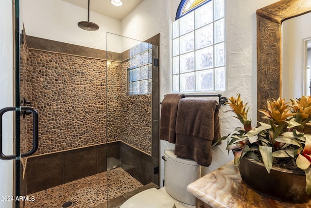 full bath with a textured wall, a tile shower, and toilet