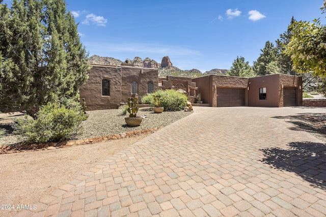 pueblo-style home featuring a garage, decorative driveway, and a mountain view