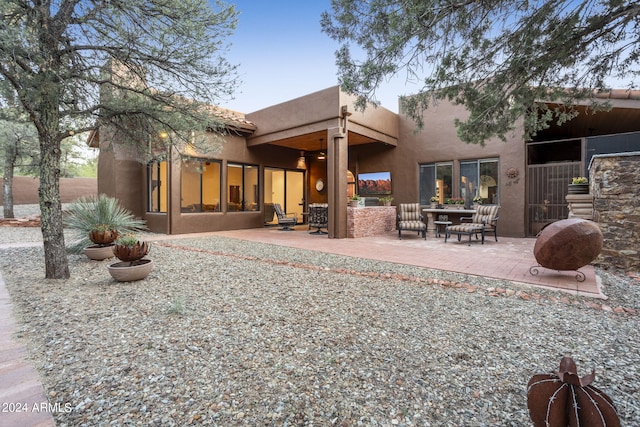 rear view of property with outdoor lounge area, a patio, and stucco siding