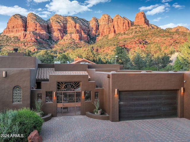 view of front facade featuring a garage, a mountain view, decorative driveway, and stucco siding