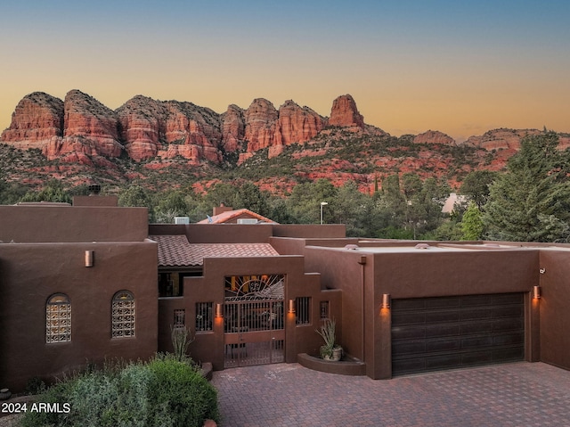 view of front of home with an attached garage, a mountain view, decorative driveway, and stucco siding