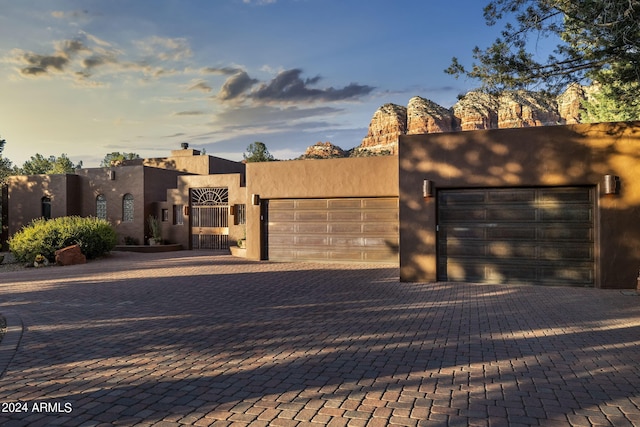 southwest-style home with an attached garage, decorative driveway, and stucco siding