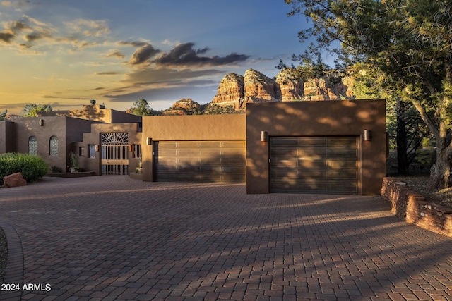 pueblo-style house featuring a garage, decorative driveway, and stucco siding