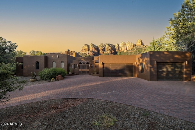 adobe home with decorative driveway and an attached garage