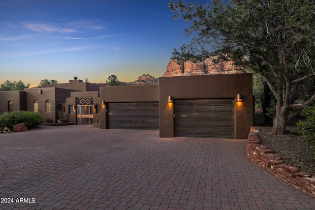 pueblo-style house featuring a garage, decorative driveway, and stucco siding