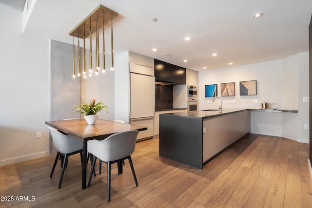 kitchen featuring sink, paneled fridge, kitchen peninsula, and light hardwood / wood-style floors