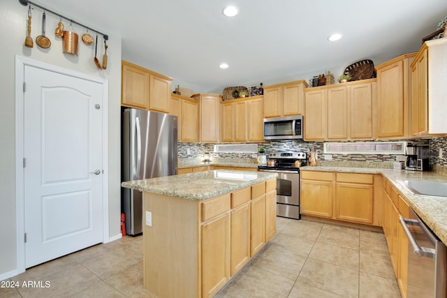 kitchen featuring a center island, light brown cabinetry, light tile patterned floors, and appliances with stainless steel finishes