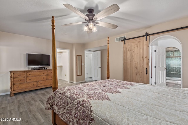15849 N 46th Pl, Phoenix, AZ 85032 - bedroom featuring wood finished floors, baseboards, a barn door, a ceiling fan, and arched walkways
