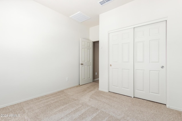 unfurnished bedroom with light colored carpet and a closet