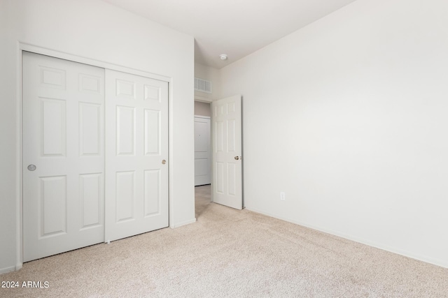 unfurnished bedroom with light carpet and a closet