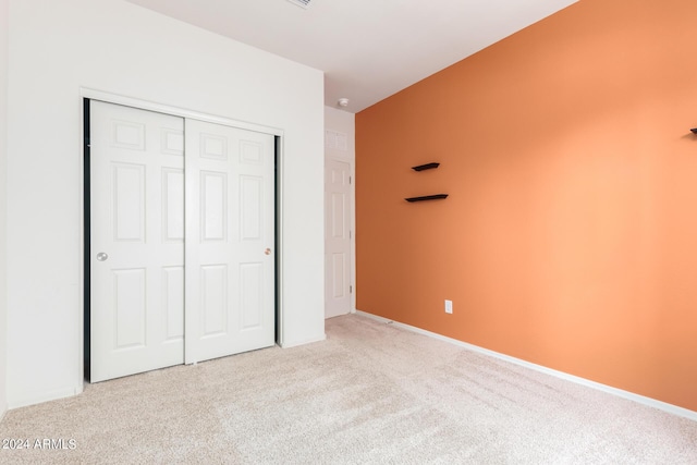 unfurnished bedroom with light carpet and a closet