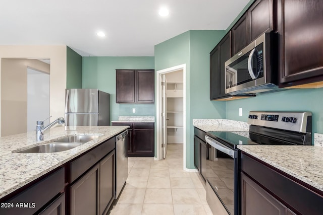 kitchen with light stone counters, sink, dark brown cabinets, and stainless steel appliances