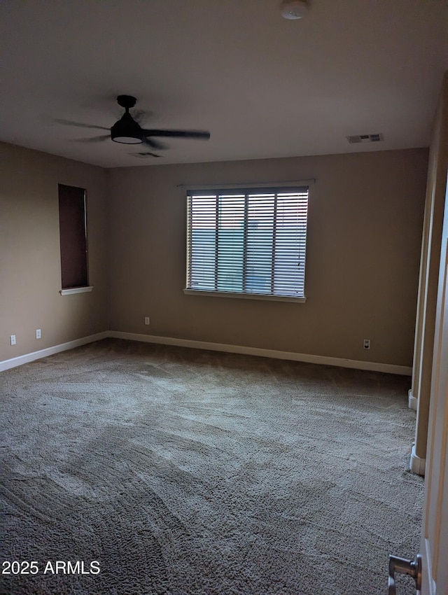 carpeted empty room featuring ceiling fan, visible vents, and baseboards