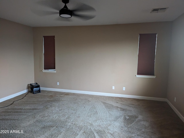 spare room featuring carpet floors, visible vents, ceiling fan, and baseboards