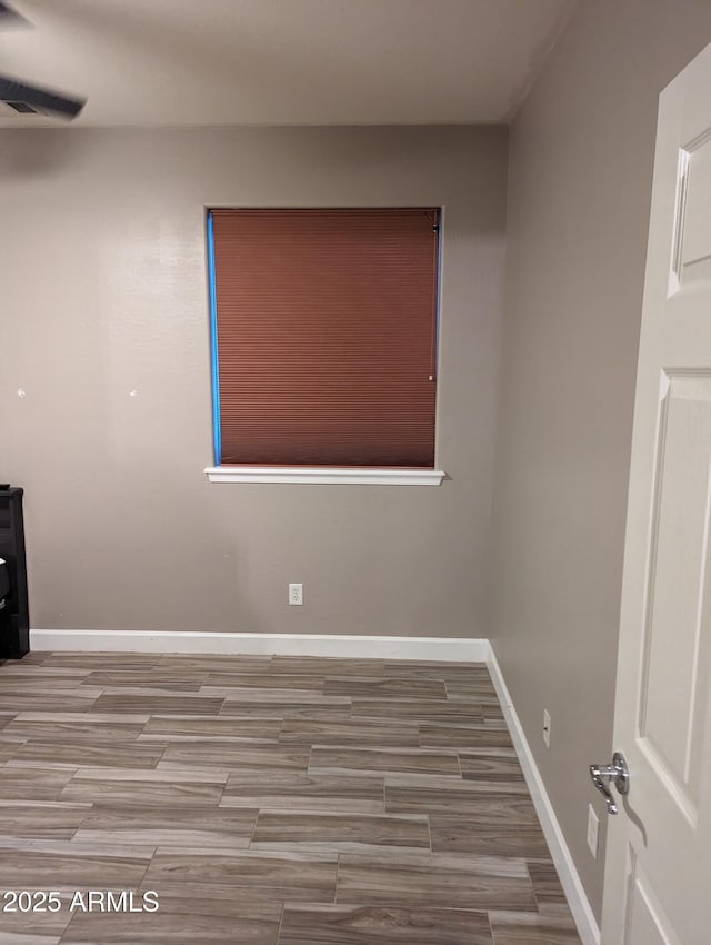 unfurnished room featuring wood tiled floor and baseboards