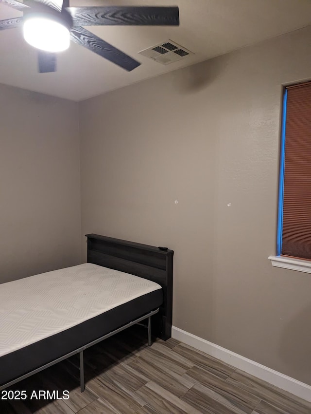 bedroom featuring baseboards, visible vents, a ceiling fan, and wood finished floors