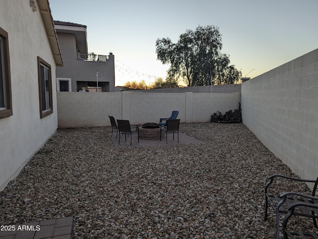 yard at dusk featuring a fire pit, a patio area, and a fenced backyard