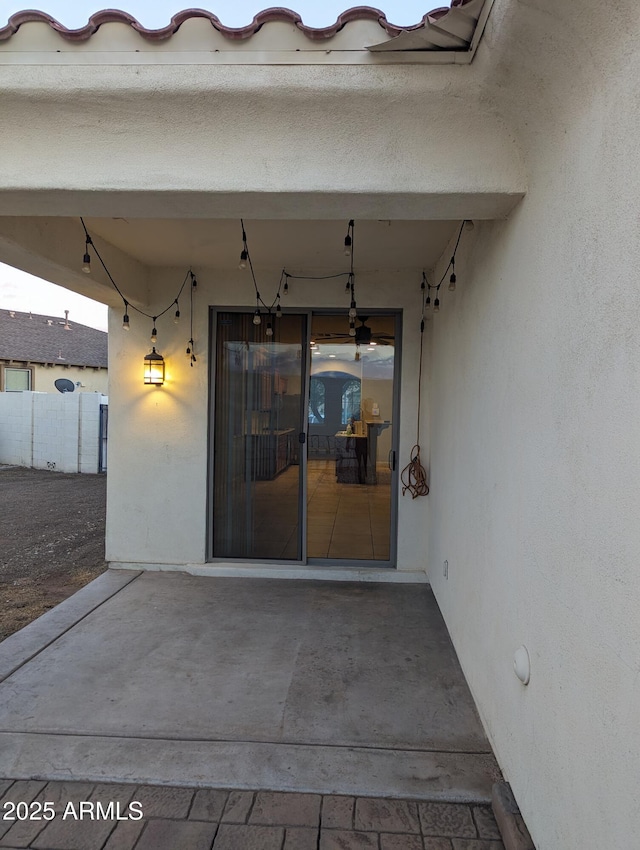 entrance to property featuring a patio area, fence, and stucco siding